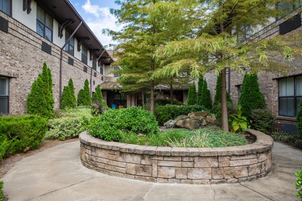 A serene courtyard with lush greenery and a stone wall pathway.