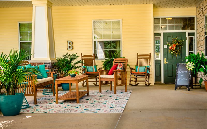 A cozy porch with wooden rocking chairs, a coffee table, decorative pillows, and potted plants.