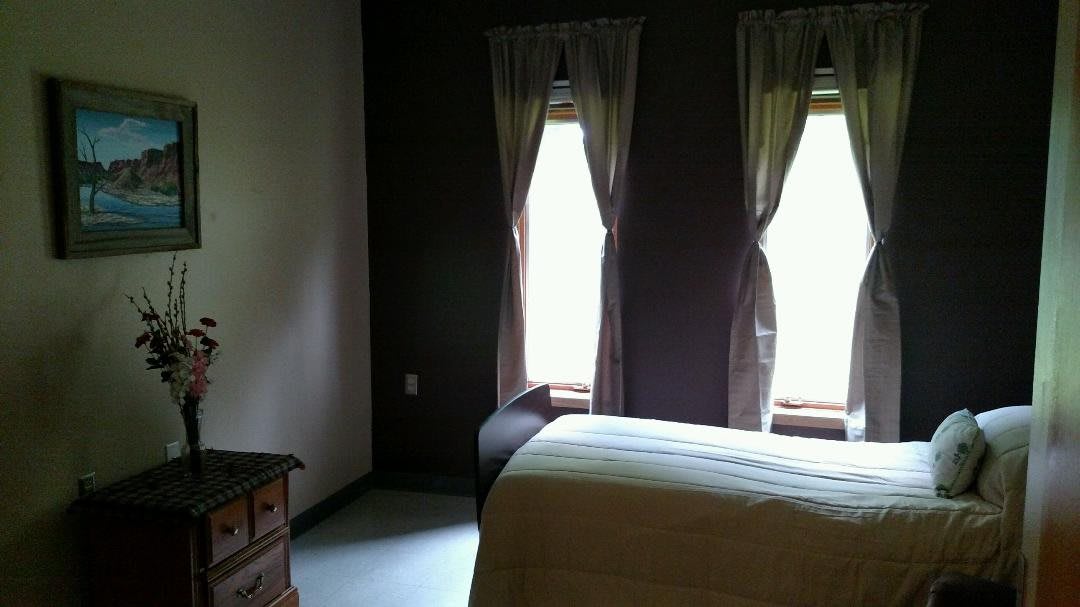 A cozy bedroom with two windows, curtains, and a bed.