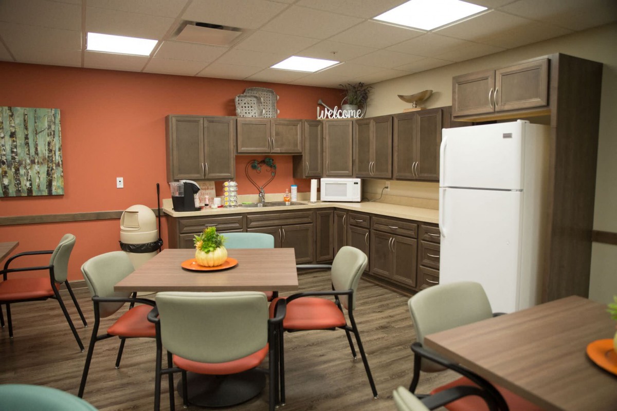 A modern kitchen and dining area with tables, chairs, and appliances.