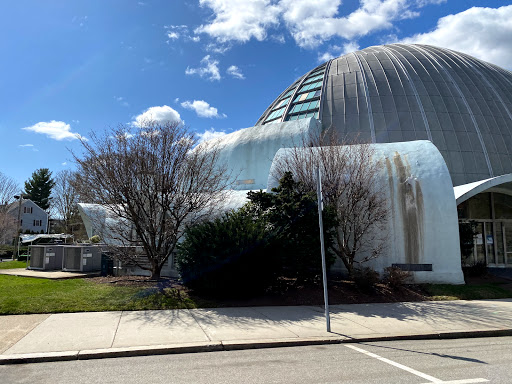 A unique architectural structure surrounded by nature under a partly cloudy sky.