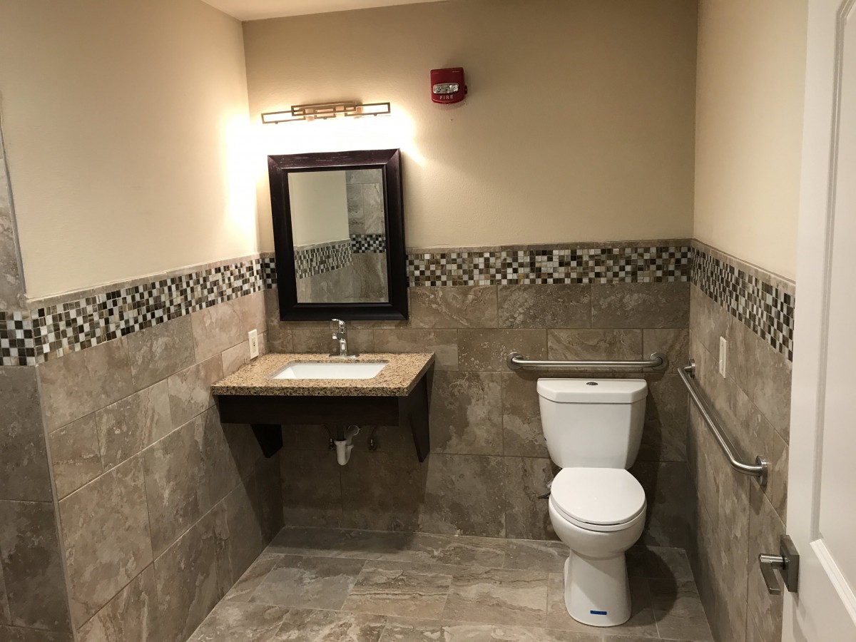 A clean and modern bathroom with a sink, mirror, and toilet.