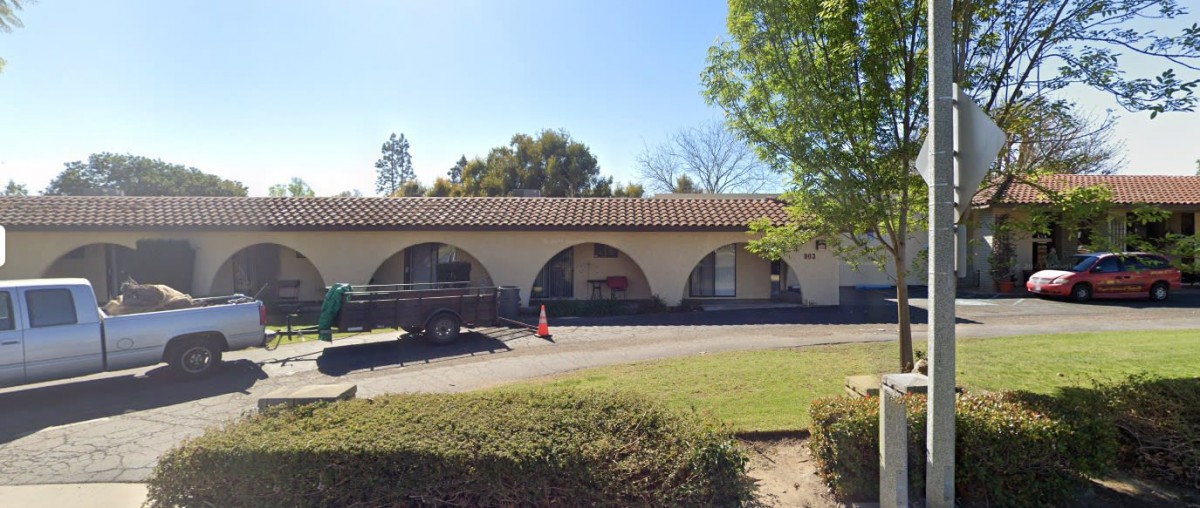 A building with arches under a clear, sunny sky surrounded by trees.