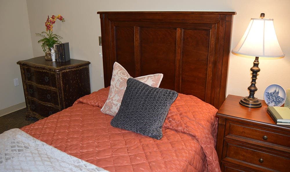 A cozy bedroom setting featuring a wooden headboard and neatly arranged pillows on the bed.