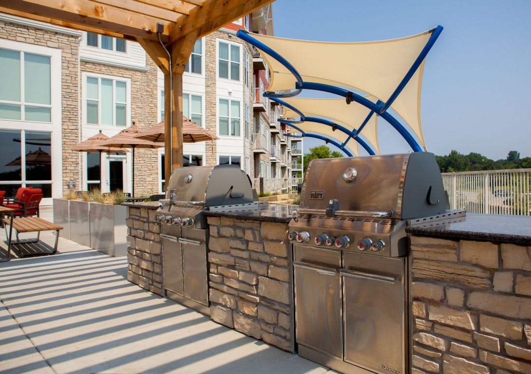 Outdoor kitchen area with grills and shade structures on a sunny day.