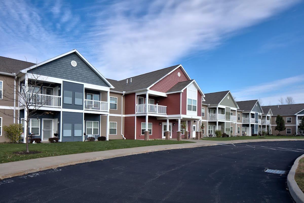 A row of modern suburban apartment buildings with colorful facades under a clear blue sky.
