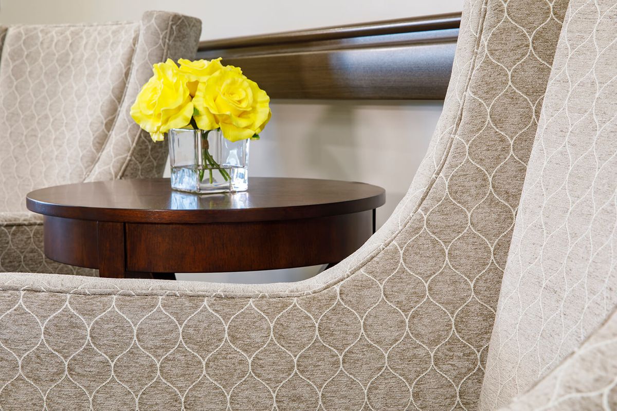A cozy interior setting featuring yellow roses in a vase on a wooden table.