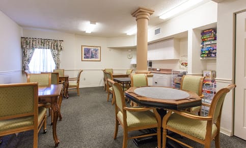 A cozy dining and kitchen area with several tables and chairs, featuring soft lighting and classical decor.