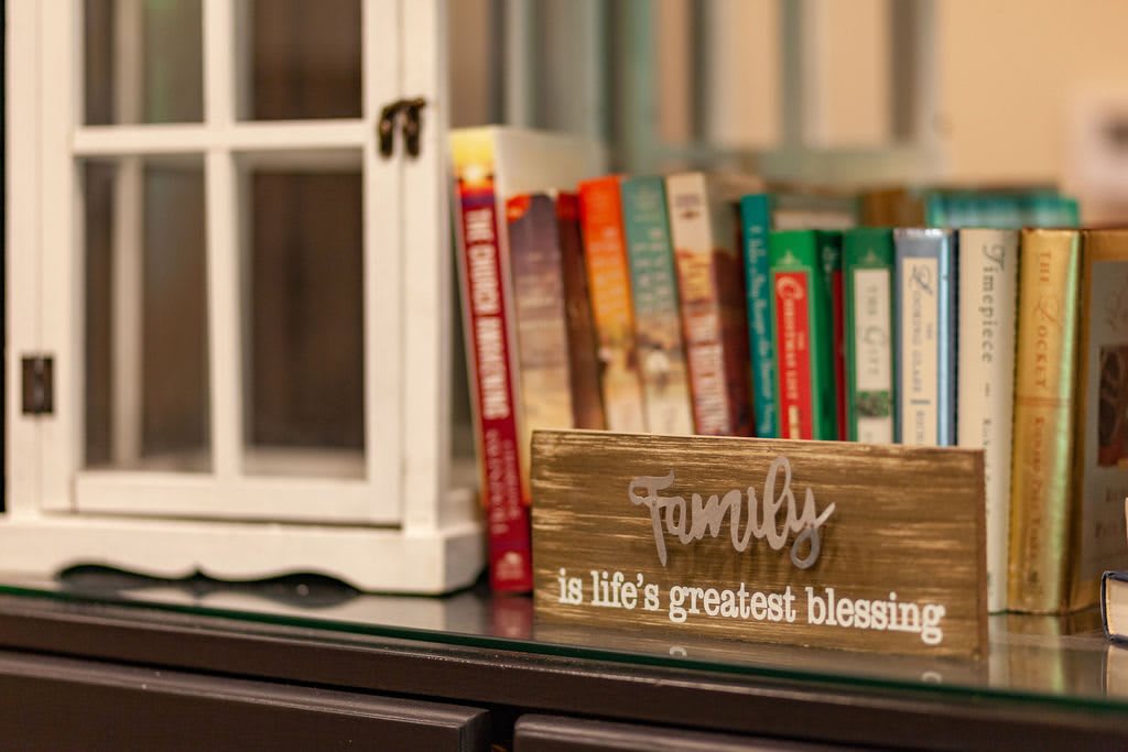A cozy bookshelf featuring a wooden sign with an inspiring message about family.