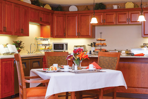 A cozy dining area with a beautifully set table, featuring fresh flowers and a warm kitchen ambiance.