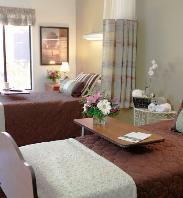 A hospital room with two beds, floral arrangements, and a calming atmosphere.