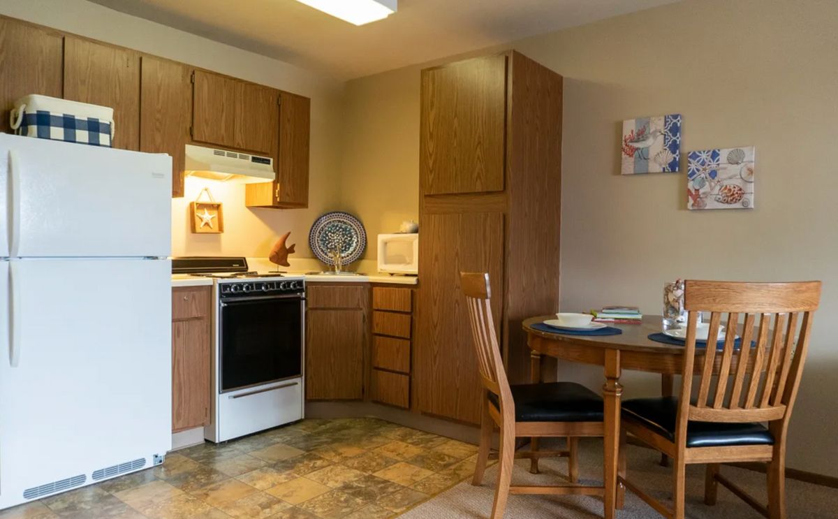 A cozy kitchen with wooden cabinets, a small dining table, and essential appliances.
