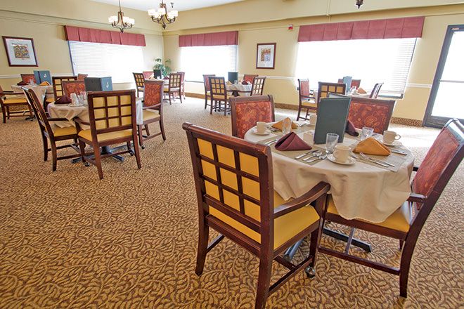A well-lit dining room with neatly arranged tables and chairs, featuring elegant table settings.