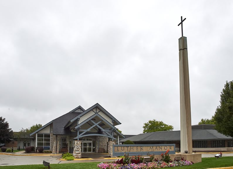 A church building with a tall cross against a cloudy sky.