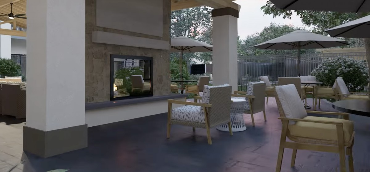 A cozy outdoor patio area featuring comfortable seating, a fireplace, and garden views.