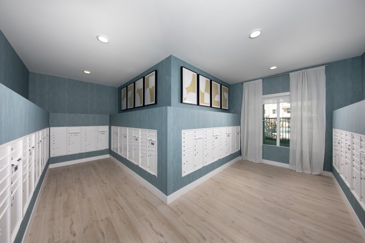 A modern interior room with blue walls, white lockers, wood flooring, and framed paintings above the lockers.