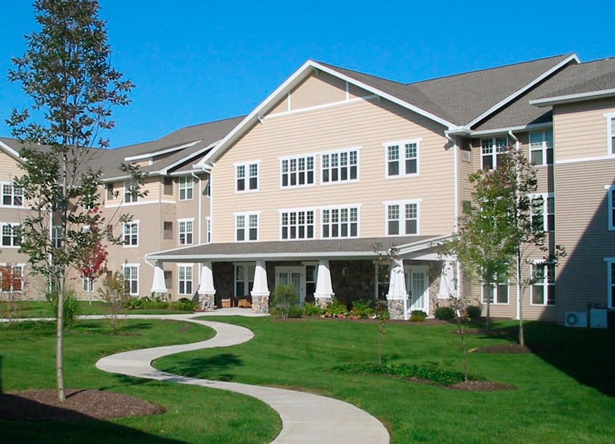 A well-maintained residential building with a winding pathway and lush green lawn.