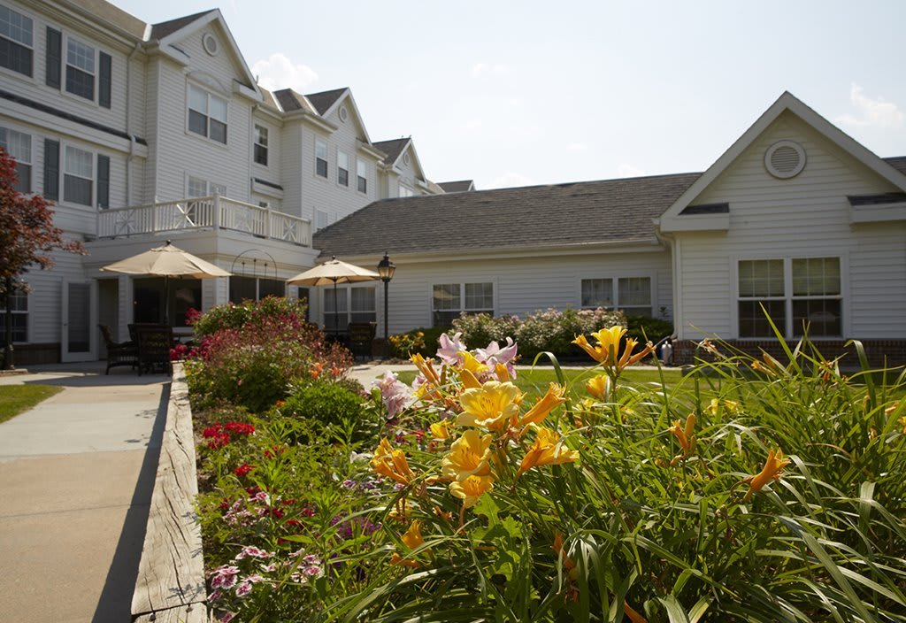 A beautiful garden in front of a large white building under a clear sky.