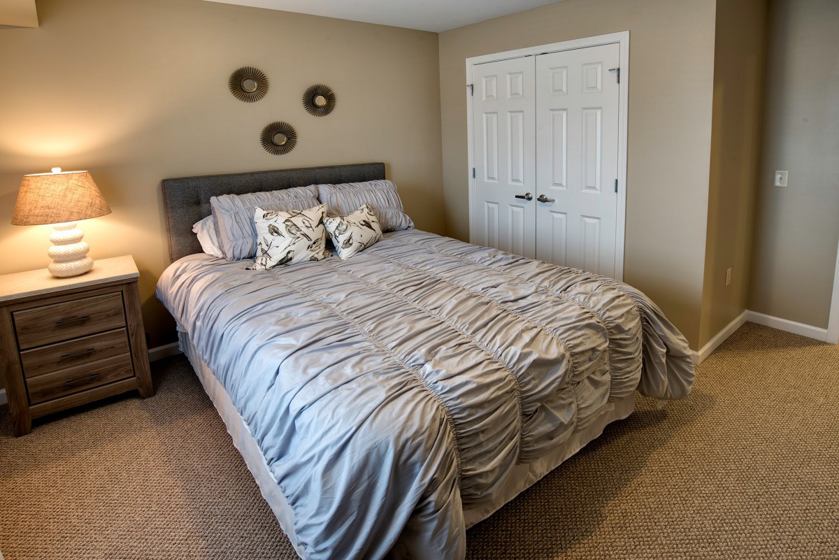 A cozy bedroom with a neatly made bed and decorative pillows.