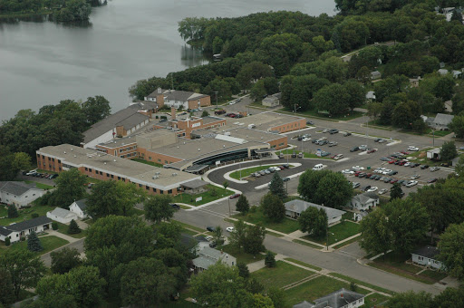An aerial view of a commercial complex near a lake, surrounded by greenery.