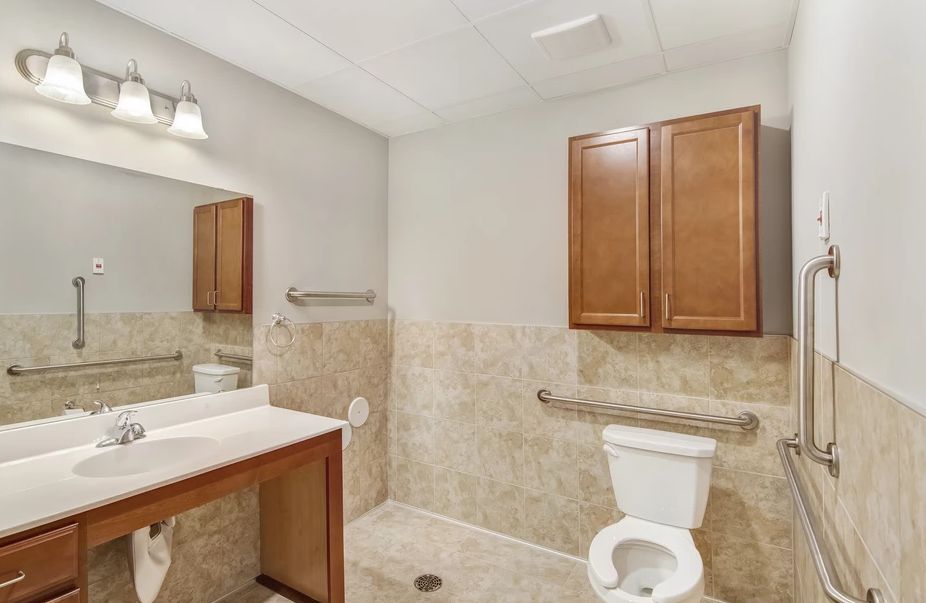 A clean and well-organized bathroom with a toilet, sink, mirror, and wooden cabinet.