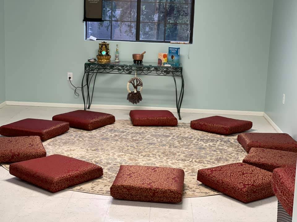 A serene indoor meditation space with cushions arranged in a circle on a rug.