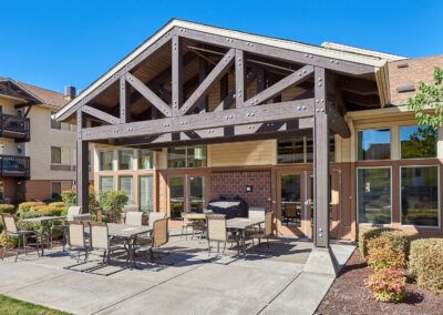 A modern outdoor patio with dining furniture, featuring wooden beams and a brick exterior.
