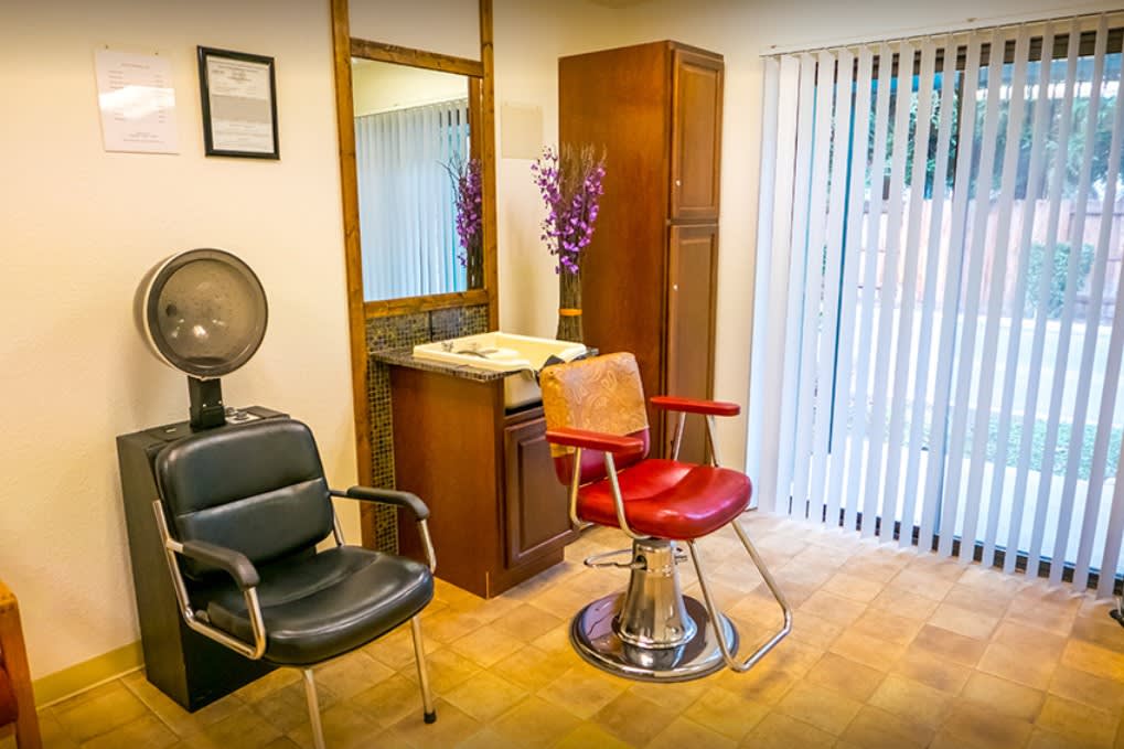 A cozy salon interior featuring stylish chairs and a large mirror.