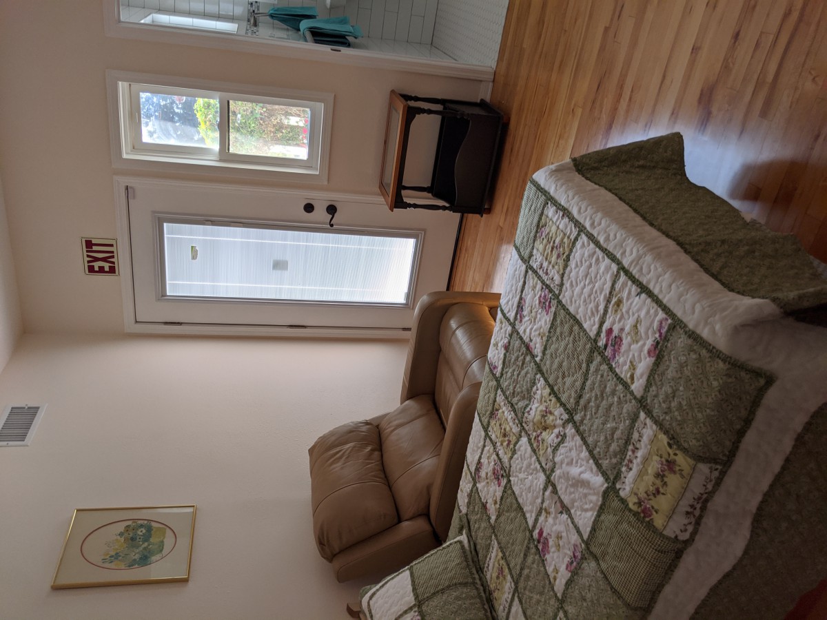A cozy living room with a quilted sofa, armchair, and wooden flooring.