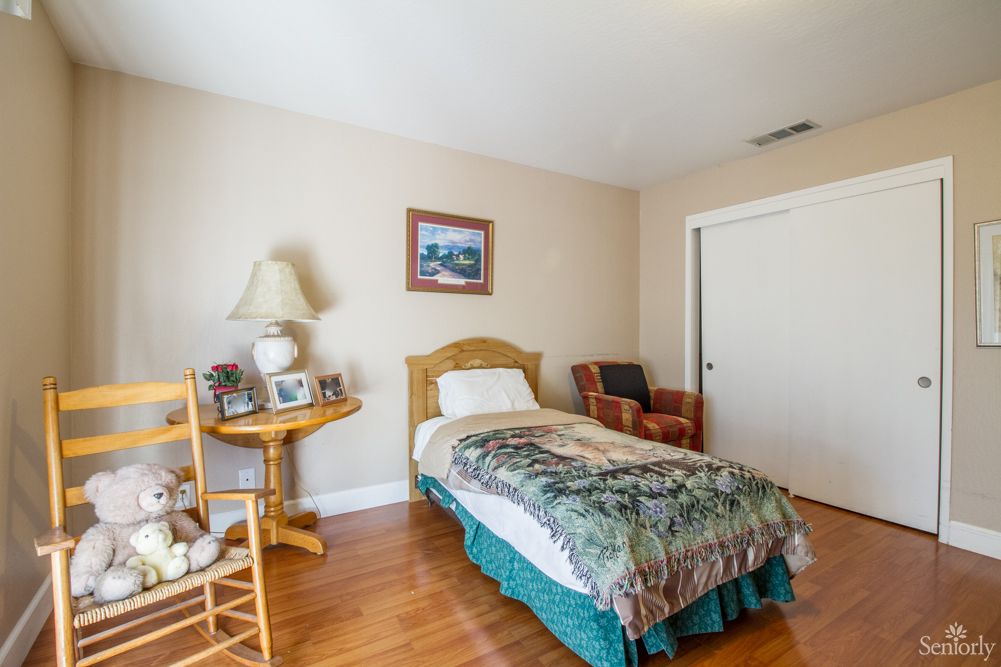 A cozy bedroom with a single bed, wooden furniture, and decorative elements.