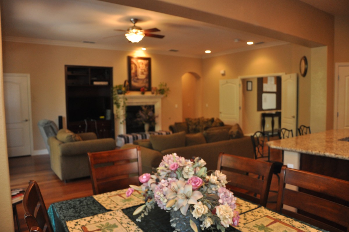 A cozy living room featuring a dining table with a floral centerpiece, sofas, and a fireplace.