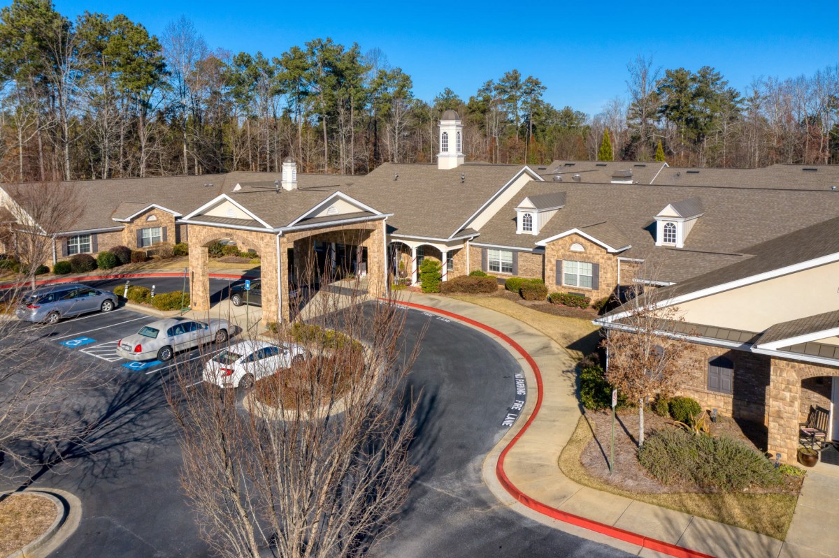 Aerial view of a residential building with a circular driveway surrounded by trees.