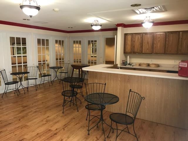 A cozy cafe interior with round tables, chairs, and a wooden counter with overhead lighting.