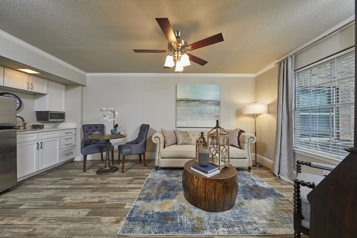 A modern living room with a comfortable sofa and wooden coffee table, featuring elegant armchairs and wall art.
