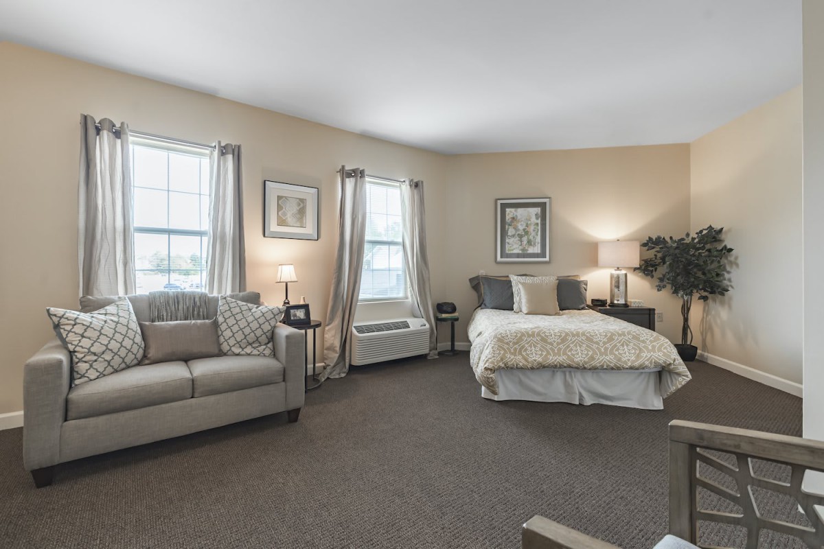 A spacious, well-lit bedroom with a cozy seating area and modern decor.