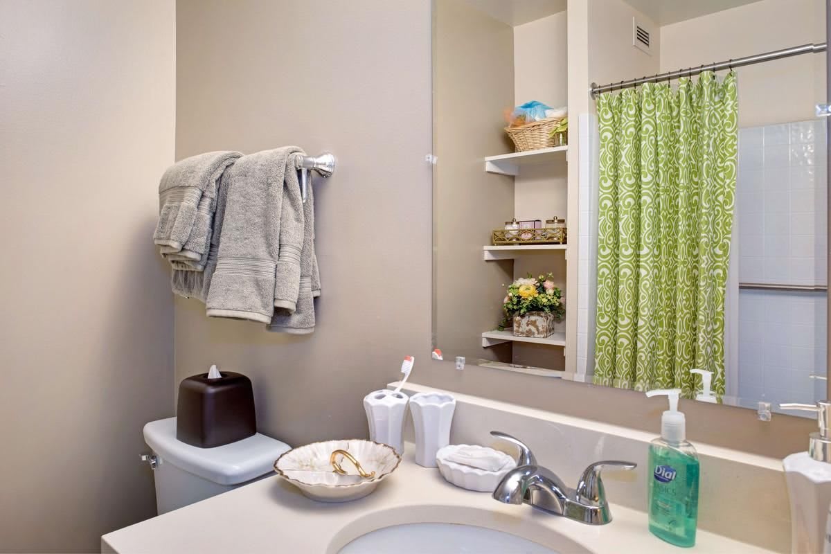 A neatly organized bathroom with towels, a sink, and a green shower curtain.