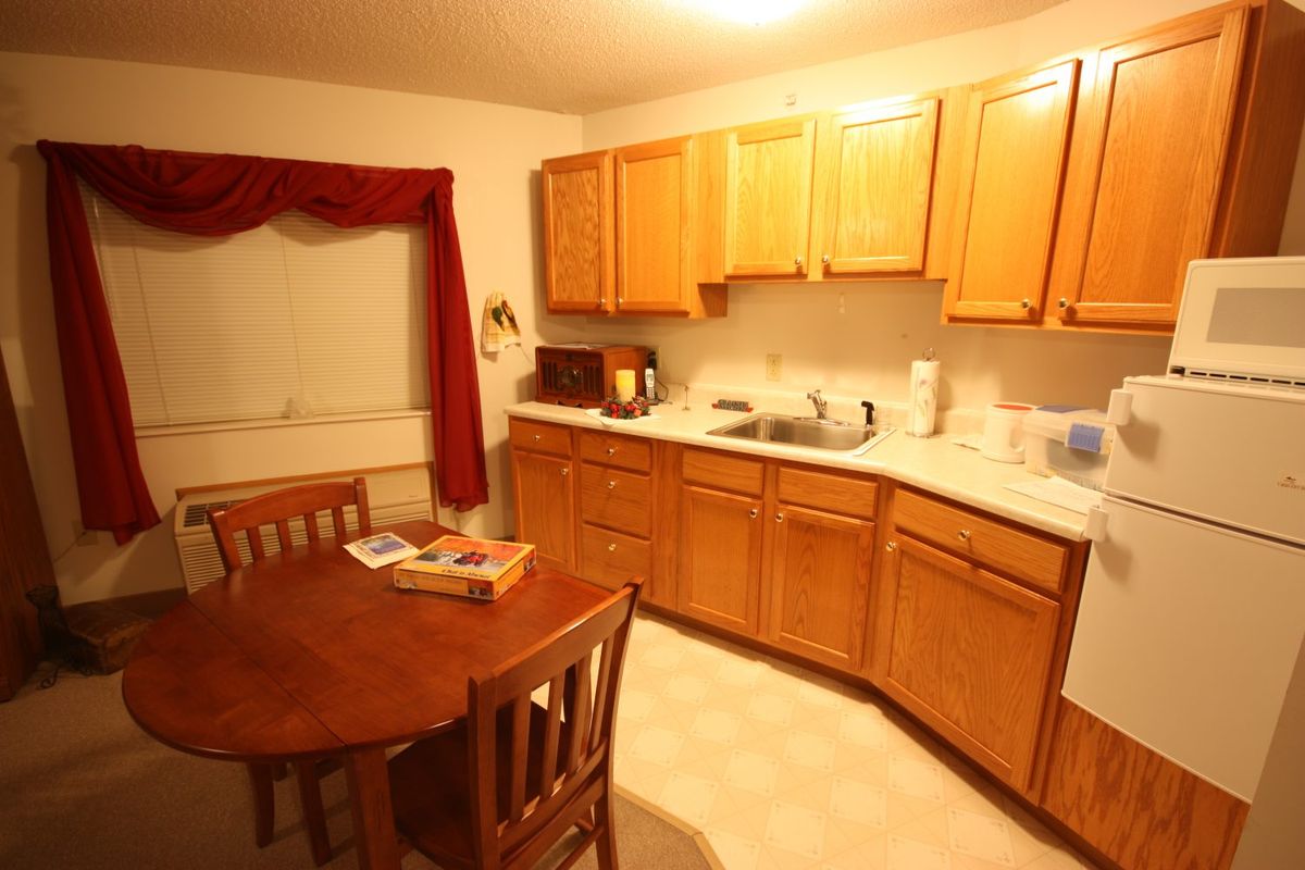 A cozy kitchen with wooden cabinets, a dining table, and chairs.