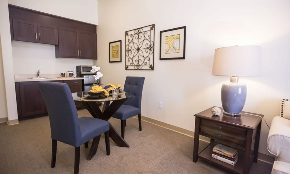 A cozy dining area with a small round table, two blue chairs, and modern decor.