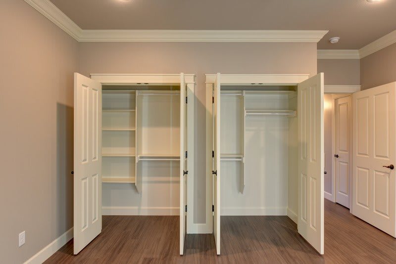 A photo of an empty double-door closet with shelving and hanging space.