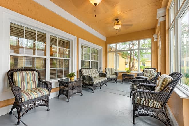 Cozy sunroom with wicker furniture and large windows.