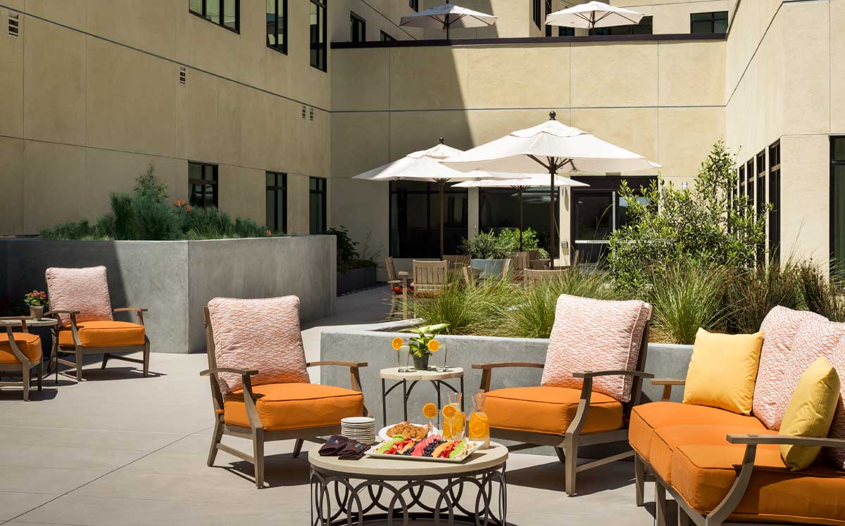 Cozy outdoor patio area with orange cushioned chairs and a table set for refreshments.