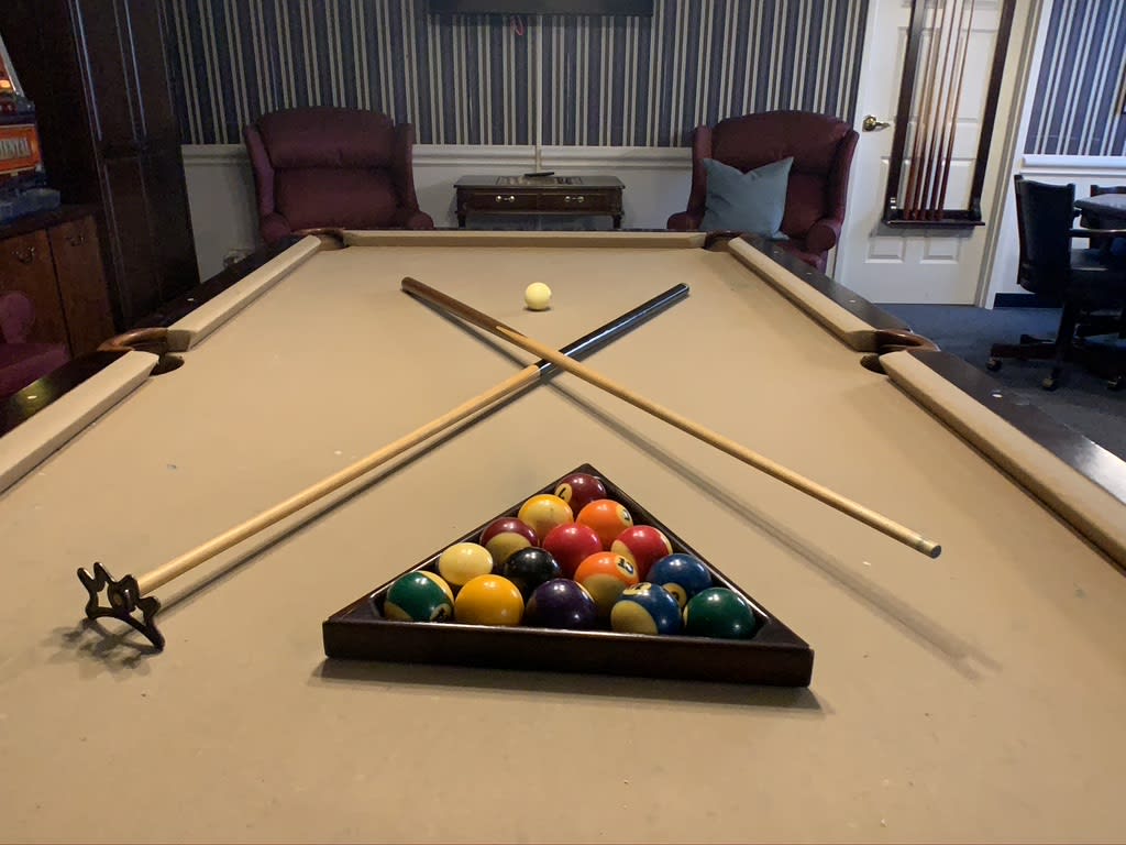 A neatly arranged billiards setup with cue sticks and racked balls on a pool table.