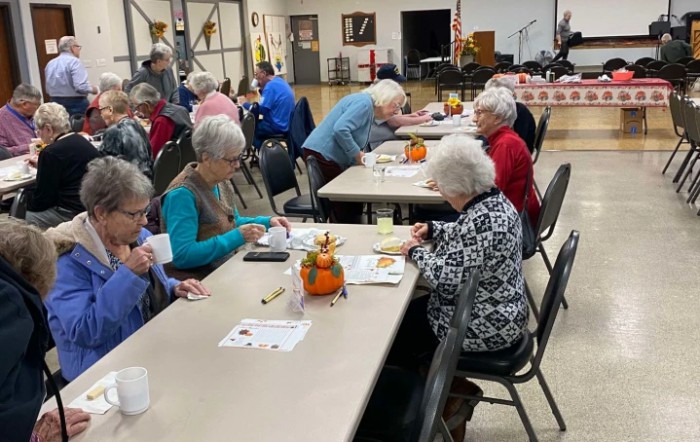 A group of seniors engaged in a crafting activity at an indoor community event.