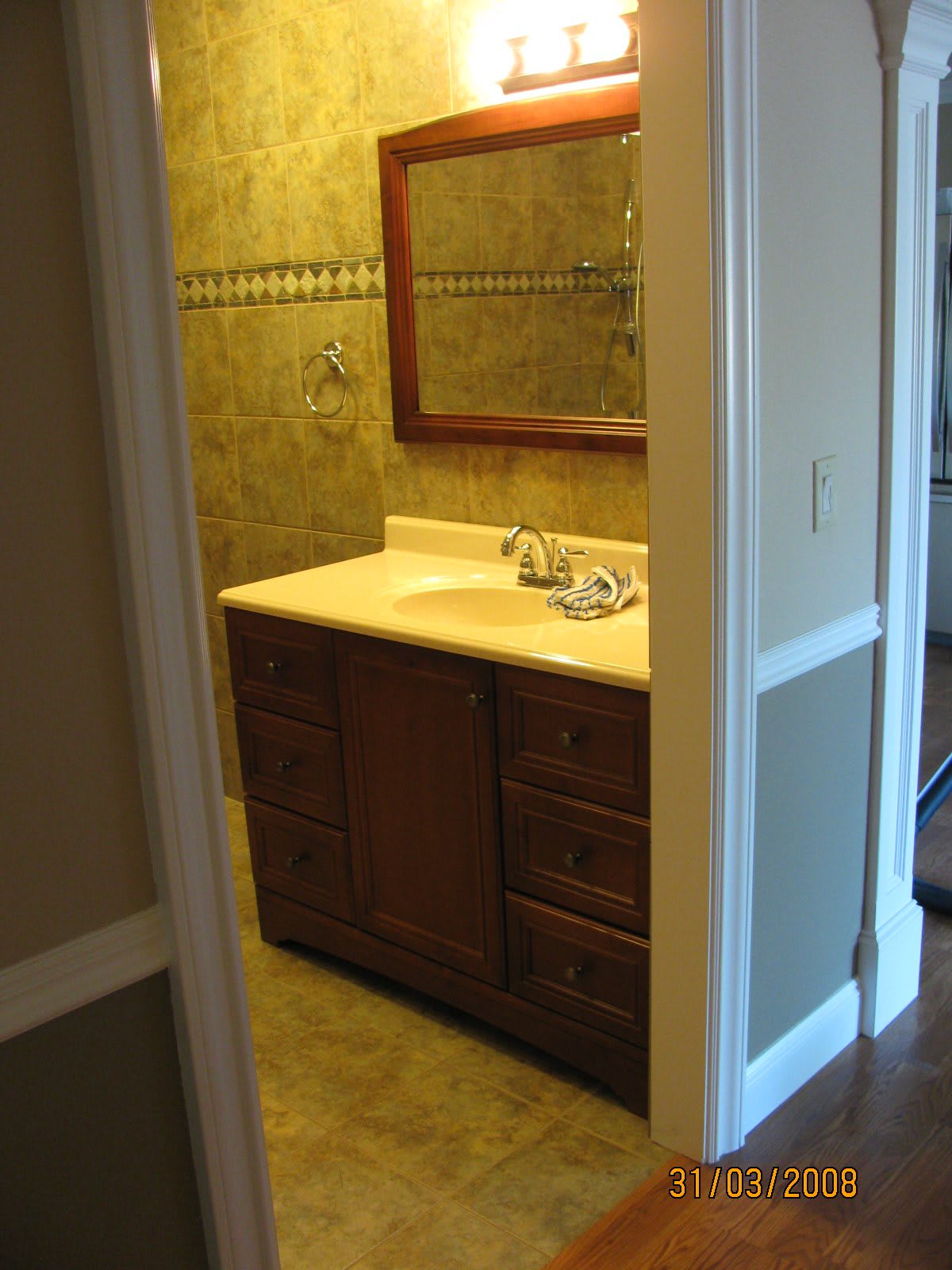 A small bathroom featuring a wooden vanity with a sink and mirror.