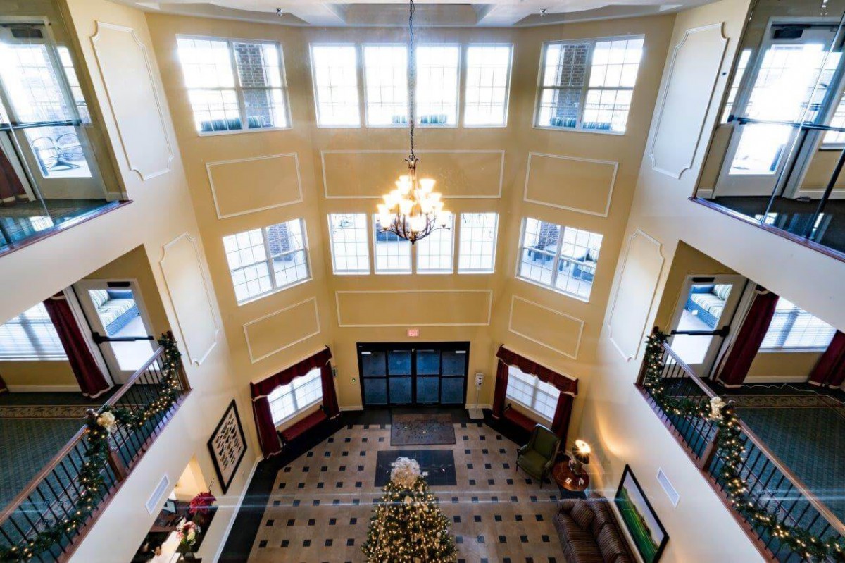 Spacious lobby with a chandelier, large windows, and elegant decor.