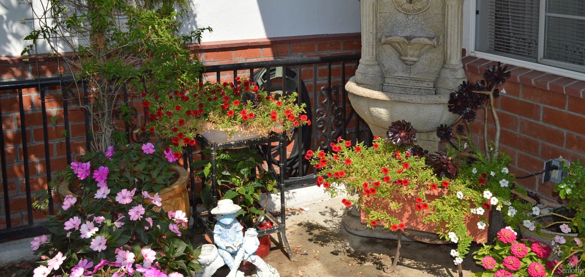 A charming garden corner featuring a small statue surrounded by vibrant flowers and potted plants.