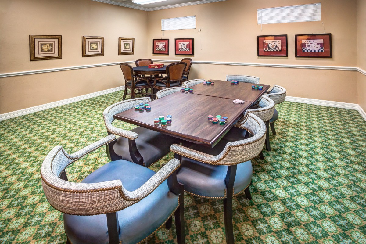 A well-furnished room with poker tables, chairs, and art on the walls.
