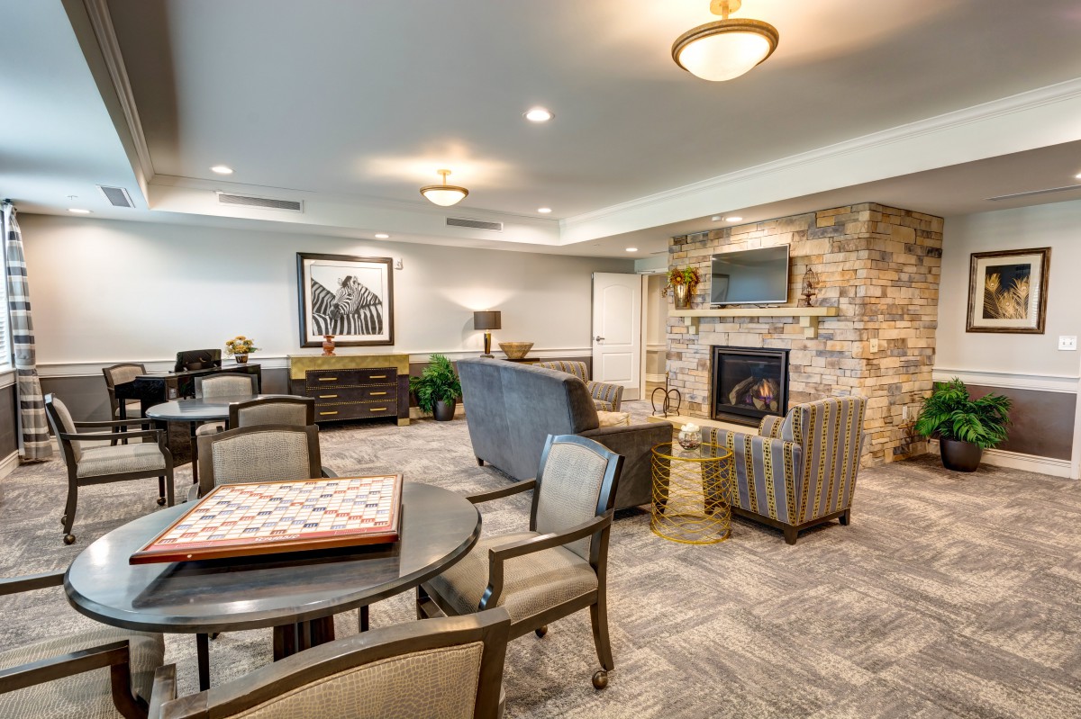A cozy living room with a fireplace, comfortable seating, and a game table.