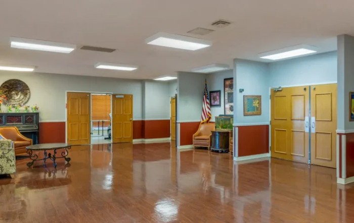 An empty hallway with wooden doors, chairs, and wall decorations.