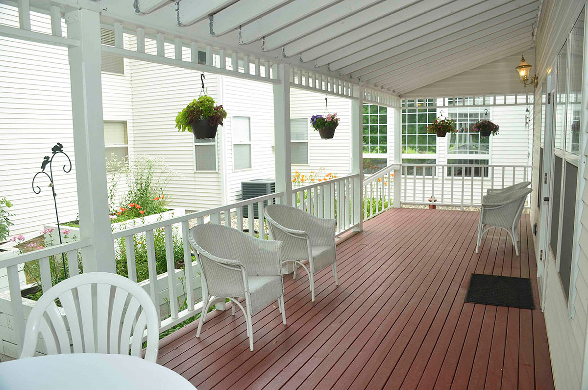 A cozy patio with white chairs and hanging plants under a pergola.